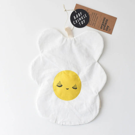 Organic Crinkle Toy Egg with white cotton and smiling yellow face, soft and stimulating sensory toy for babies.