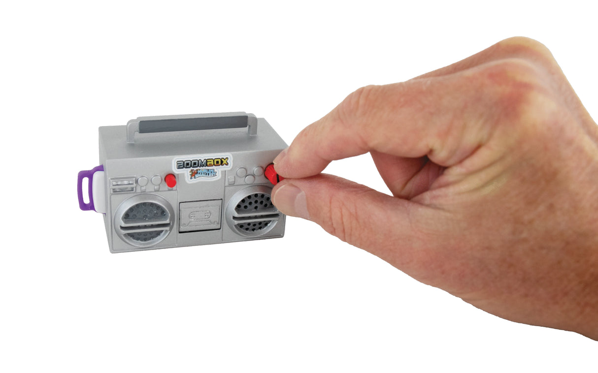 Hand adjusting red knob on small gray toy boombox with black speakers against white background