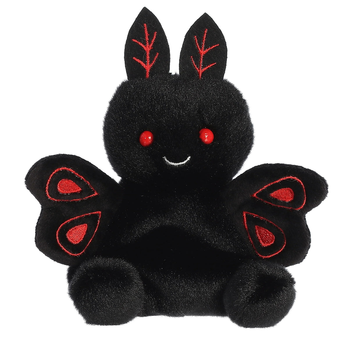 Small black plush toy with red eyes and embroidered red wing details smiling gently sitting upright