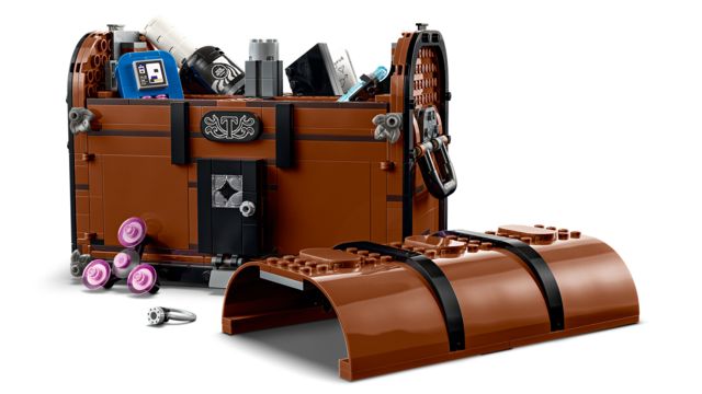 Brown toy trunk with black straps and assorted miniature accessories spilling out on a white background