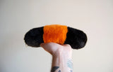 Hand holding a soft, weighted plush Wooly Bear Caterpillar with black and orange faux fur details