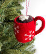 Handmade red felt ornament shaped like a hot chocolate mug with snowflake design and marshmallows hanging on a Christmas tree branch