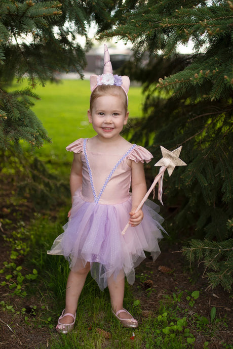 Deluxe Sparkle Star Wand held by smiling girl in pink tutu and unicorn headband outdoors among green trees.