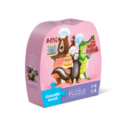 12pc Sweet Treats Puzzle box with bear, skunk, and crocodile holding colorful cakes on a pink background.
