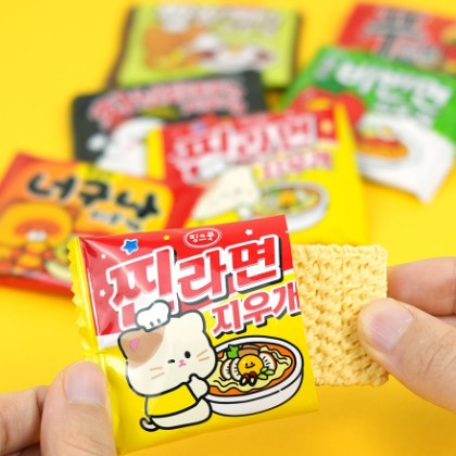 Hand holding a ramen noodle-shaped eraser with colorful playful packaging in the background