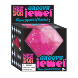 Bright pink glittery squishy jewel toy in black packaging labeled Nee Doh Groovy Jewel for kids ages three and up
