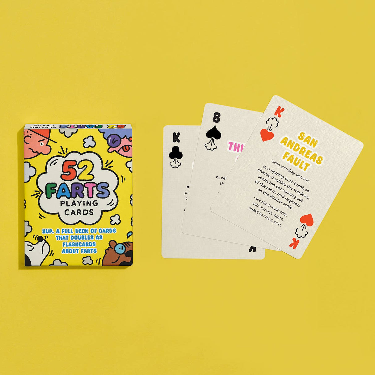 Colorful box and three playing cards from the 52 Farts deck with humorous fart-related facts on a yellow background