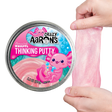 Shimmering pink Amazing Axolotl Thinking Putty being stretched beside its colorful tin packaging with playful axolotl design.