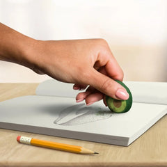 Avocado Erasers held over a sketchbook beside a pencil