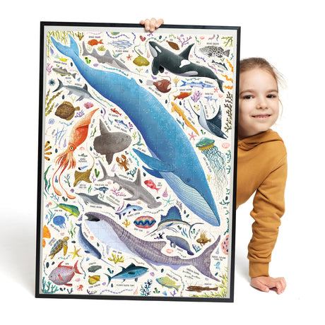 200pc PuzzLove Ocean Animals Puzzle showing diverse colorful ocean creatures including whales, squid, and fish held by a child.