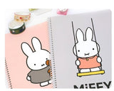 Two spiral notebooks featuring simple cartoon bunny illustrations, one in a grey outfit holding a teddy and the other on a swing wearing pink