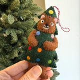 Handmade felt ornament of a brown bear dressed as a Christmas tree with colorful wool decorations hanging by loop