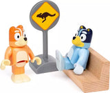 Bluey Train toy set with Bluey and Bingo figures beside a kangaroo road sign and wooden bench