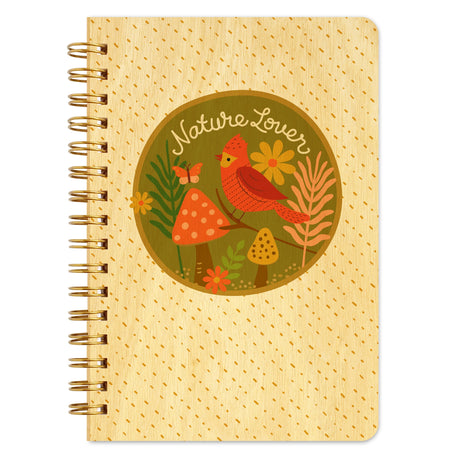 Spiral-bound notebook with beige cover featuring nature-themed illustration of bird, mushrooms, flowers, and text