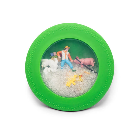 Round green sensory toy with clear center containing farm animal figurines, a farmer, and small translucent beads inside