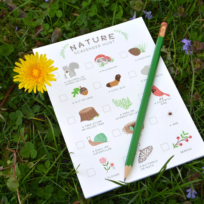 Nature Scavenger Hunt Game notepad with illustrated checklist and pencil on grass for outdoor activities.
