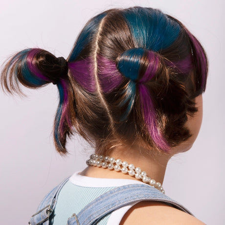 Back view of a girl with playful blue and purple temporary hair chalk in styled hair buns.