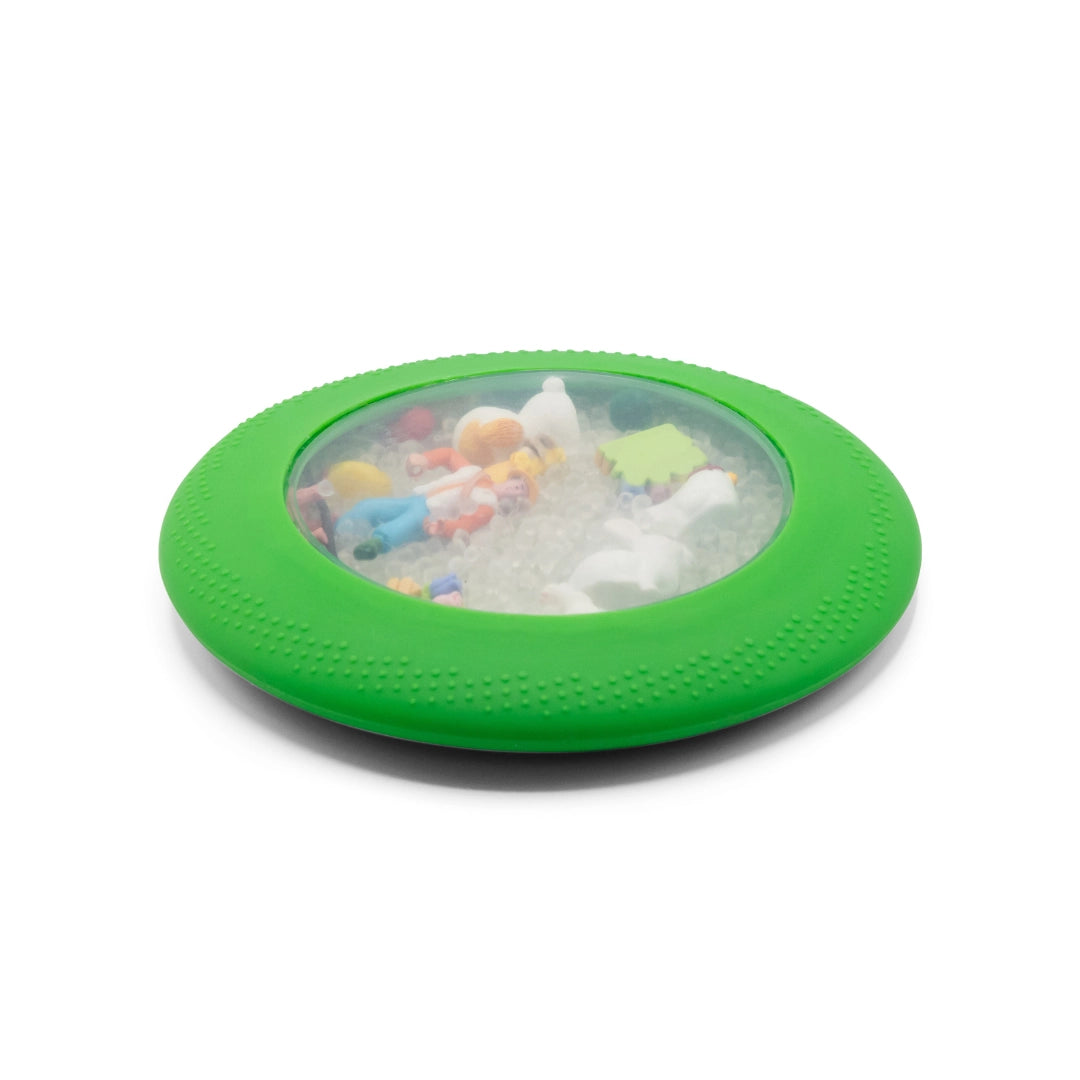 Green circular sensory toy with clear center containing miniature farm animals and small white beads inside