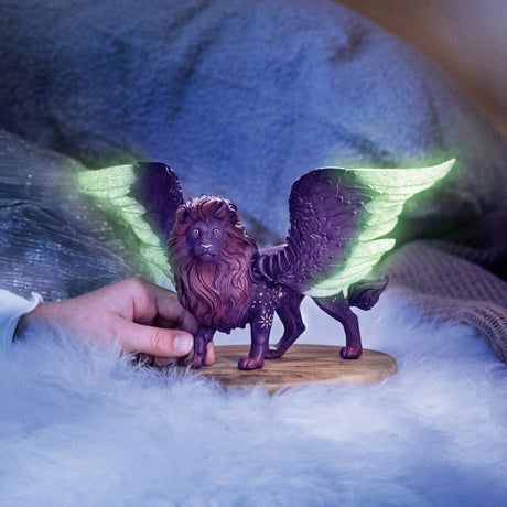 Bayala | Moon Lion figurine with glowing wings and starry dark fur held by a hand on a soft surface.