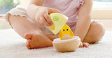 Toddler playing with colorful wobble stacker toy revealing a hidden chick inside wooden base on carpet