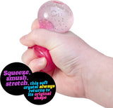 Hand squeezing a pink glittery squishy crystal toy that stretches and bounces back to original shape
