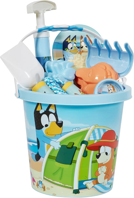 Blue plastic bucket with cartoon dog beach scenes filled with blue and orange sand toys including rake and shovel