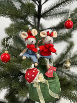 Two festive tiny mice in red sweaters and hats sitting on a Christmas tree branch with ornaments nearby