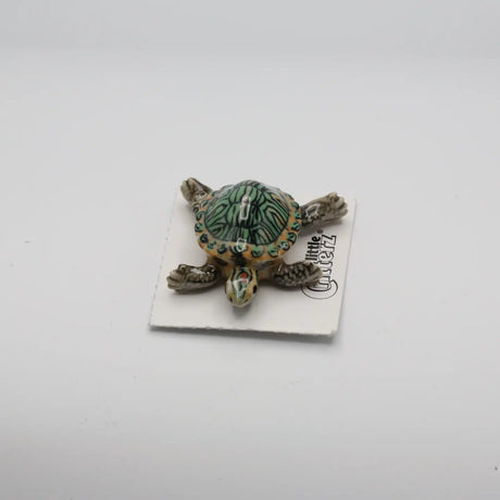 Critterz Bask Red-Eared Slider Turtle miniature porcelain figurine with detailed hand-painted shell and limbs resting on card.
