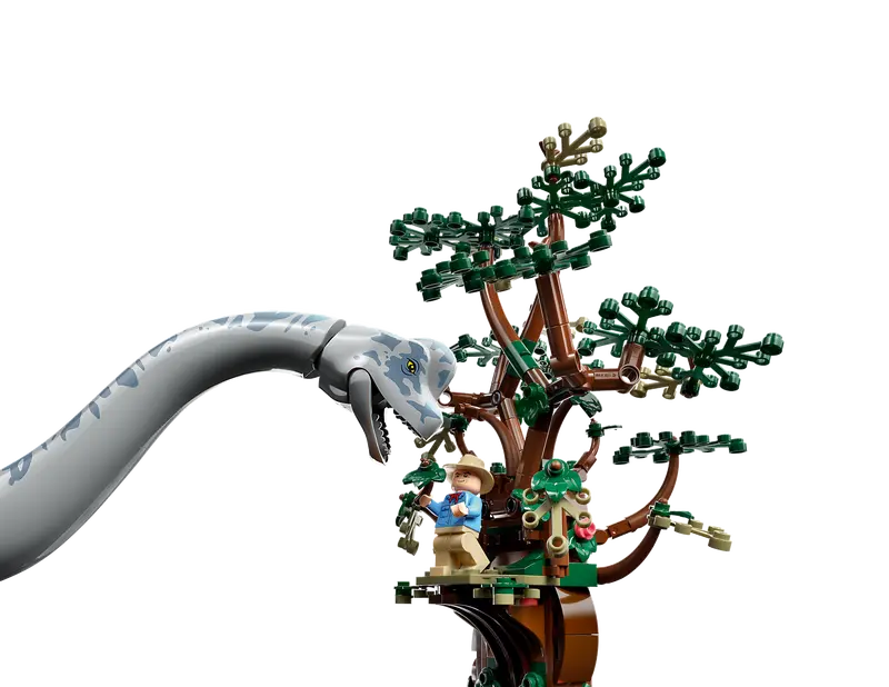 LEGO Brachiosaurus looking at a minifgure of a man standing at the top of a LEGO tree.