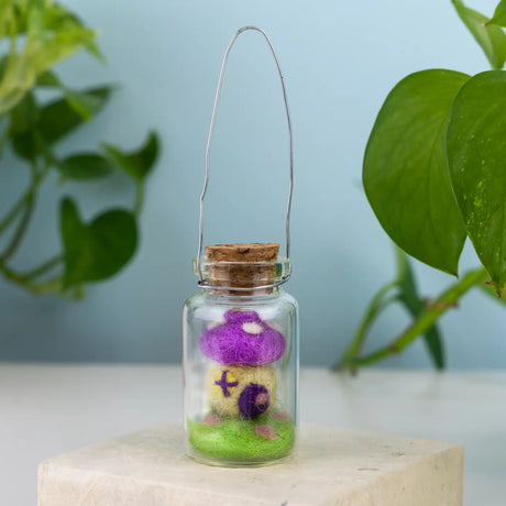 Tiny Mushroom House Bottle Ornament showing a miniature purple toadstool home inside a glass bottle with a wire hanger.