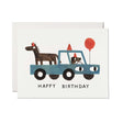 Birthday card featuring a blue truck with a dog and horse wearing party hats and a red balloon on white background