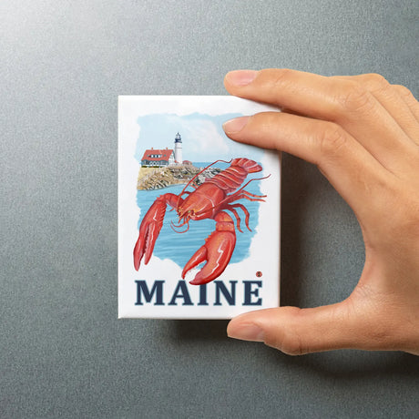 Hand holding Maine Lobster & Portland Head Magnet with lobster and lighthouse on eco-friendly paper, 3.5 x 2.5 inches.