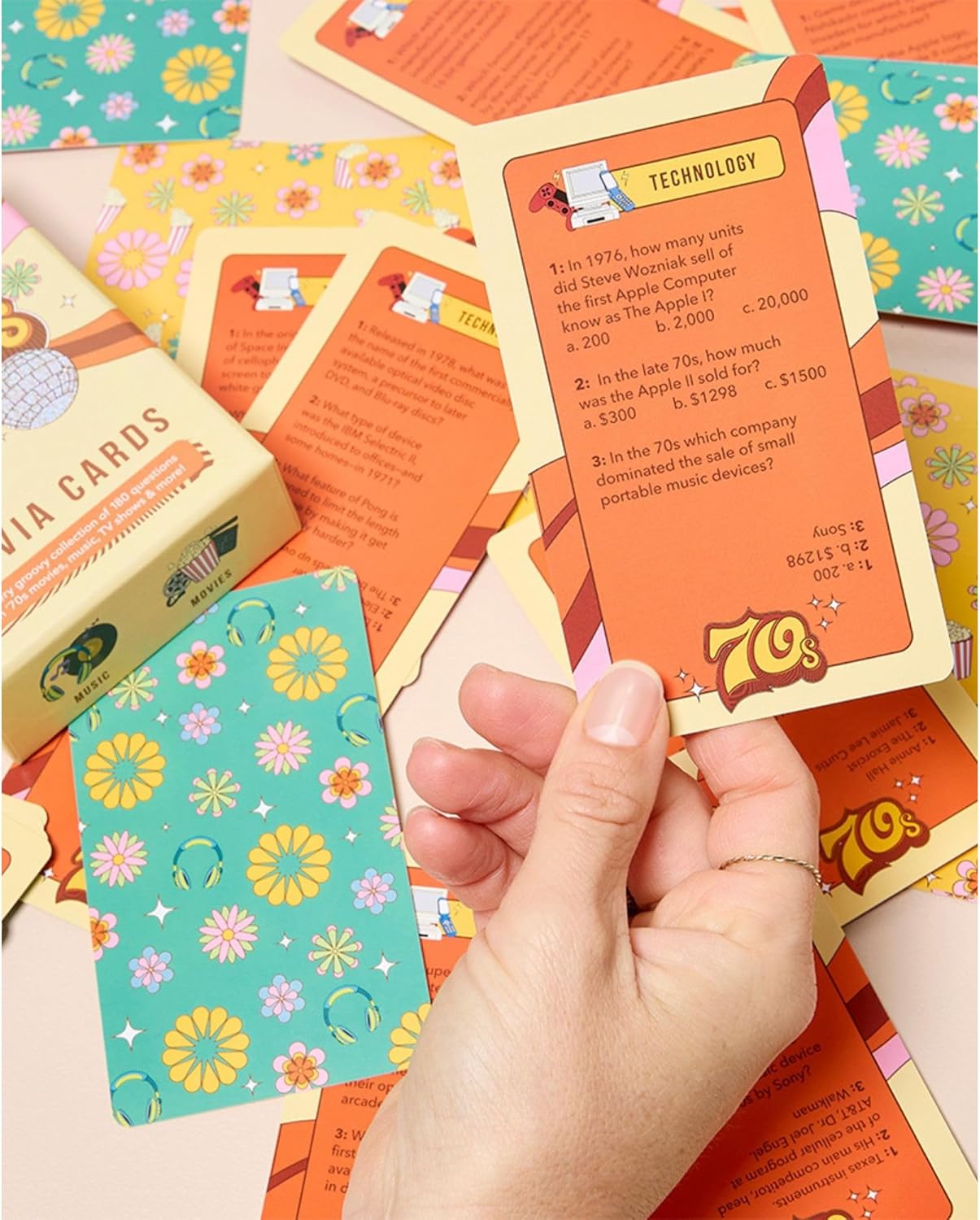 Hand holding a 70s trivia card about technology surrounded by colorful retro-themed game cards and box.