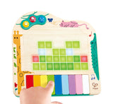 Child playing with a colorful pixel piano toy featuring light-up keys and animal illustrations on a wooden base
