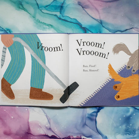 Open pages of a colorful children’s book showing a person vacuuming near a playful dog and cat with text "Vroom! Vrooom!