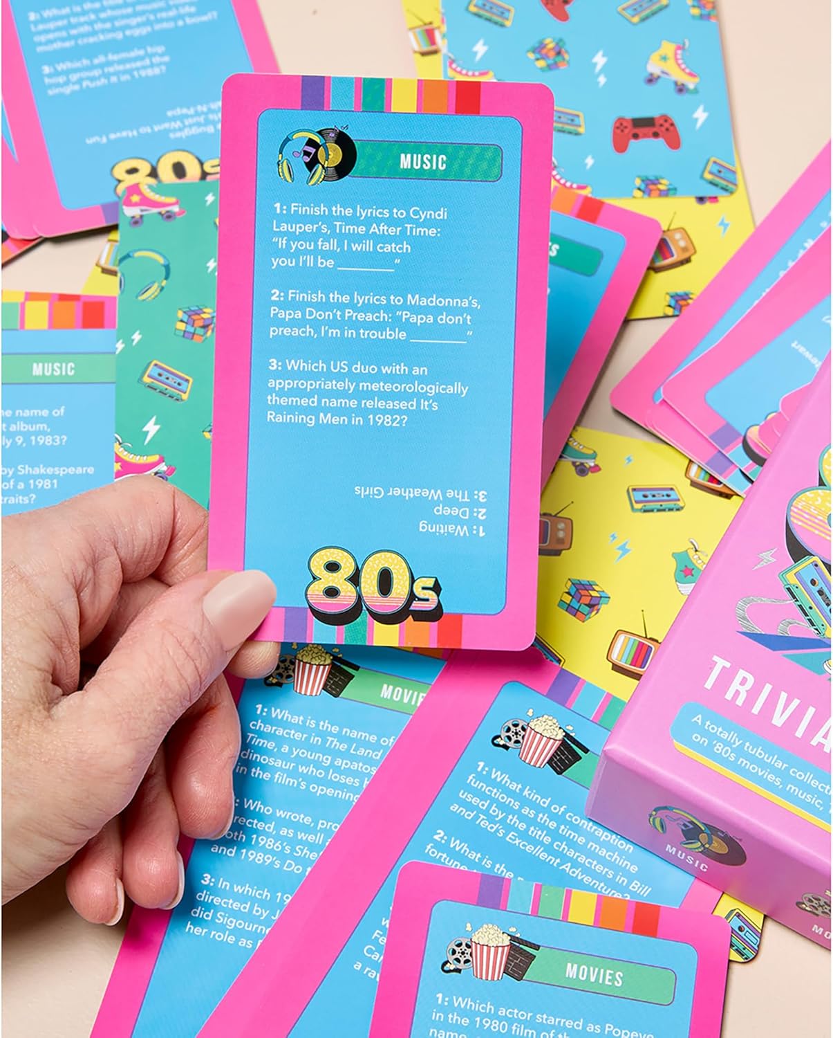 Hand holding a colorful 80s trivia card featuring music questions with retro game and pop culture icons in the background.