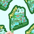 Hand holding colorful Maine map sticker highlighting major cities and landmarks with Pine Tree State text