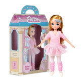 Lottie Ballet doll wearing pink tutu, wraparound cardigan, leg warmers, ballet shoes, and sparkly headband standing beside its packaging.