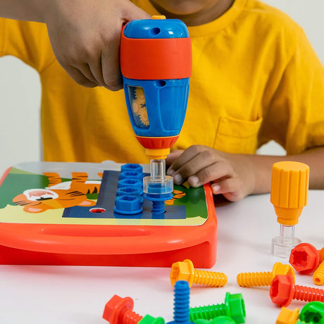 Child using a colorful toy drill to fasten bolts onto a learning board with alphabet and numbers designs