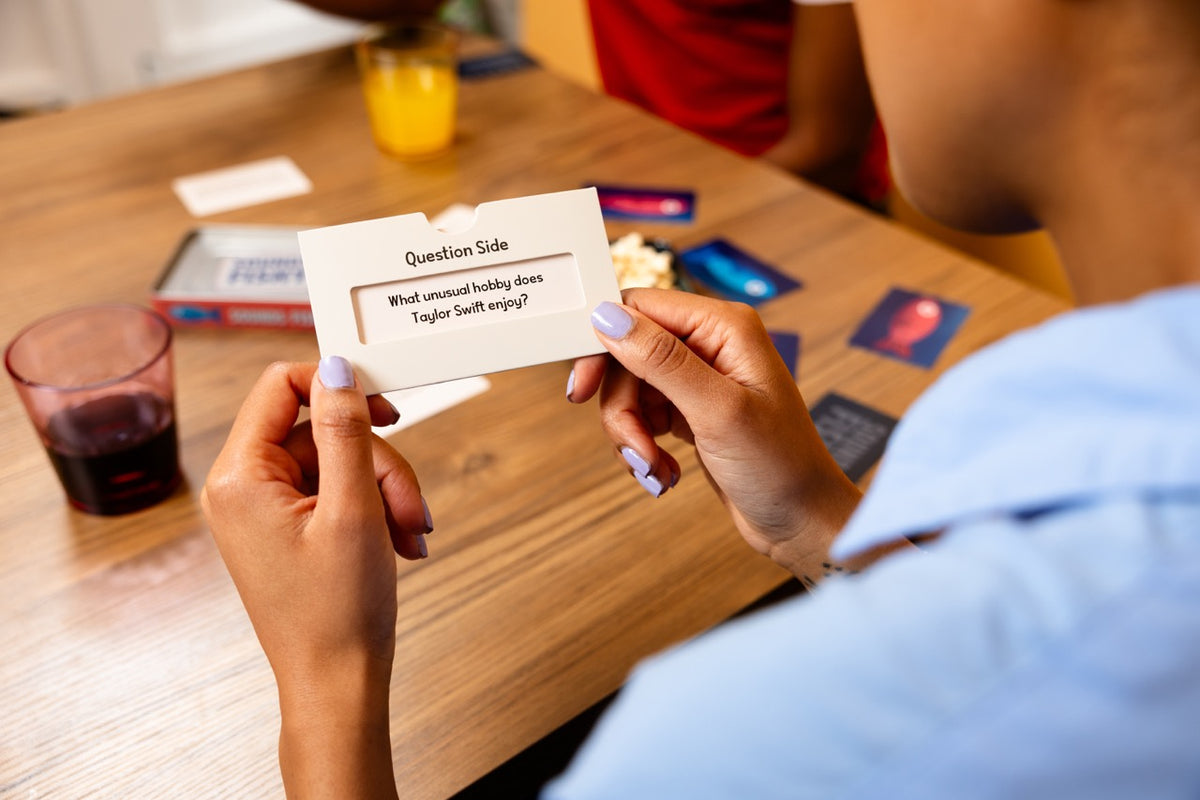 Sounds Fishy Travel Tin card game with a question card being read at a table