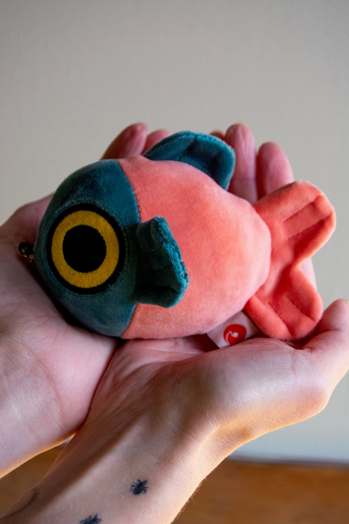 Soft and squishy mochi fish fry plush keychain held gently in hands showing its round, colorful design and tiny chain attachment