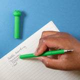 Erasable Gel Pen | Frog green pen with frog topper shown writing in a lined notebook