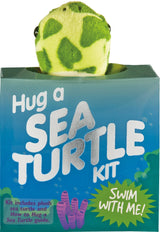 Plush mini sea turtle peeking out of a blue box labeled Hug a Sea Turtle Kit with an educational guide inside.