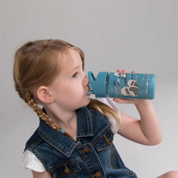 Young girl with braided hair drinking from a blue bottle decorated with bear illustrations against a neutral background