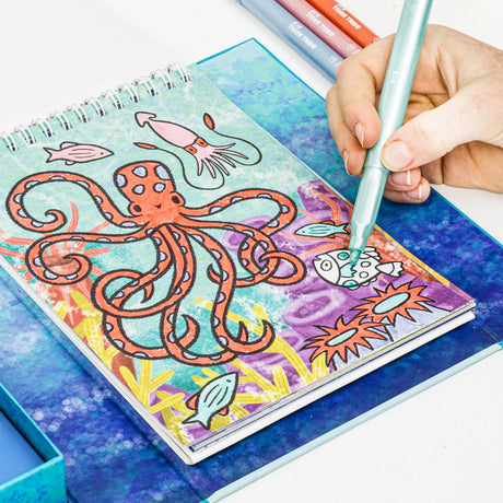 Child coloring a vibrant octopus and sea creatures in a spiral-bound activity book from the Sea Life set