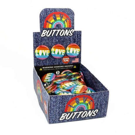 Display box filled with LOVE Button pins featuring rainbow design, 1.25 inches in diameter, perfect to spread the love.