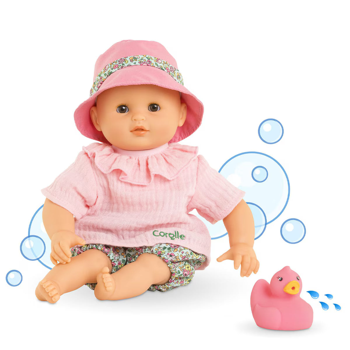 Baby doll wearing pink floral hat and bloomers sitting next to a pink rubber duck with water droplets