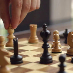Hand moving a wooden chess piece across a chessboard during a game