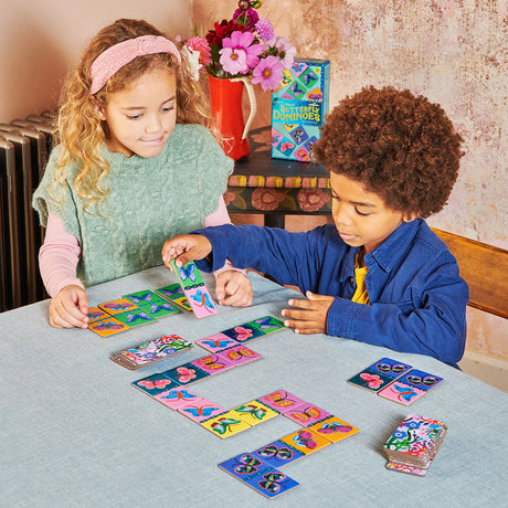 Two children playing Giant Shiny Butterfly Dominoes with colorful holographic butterfly tiles on a table.