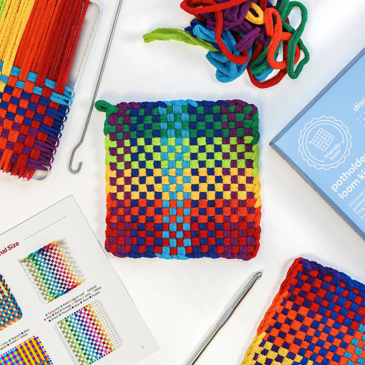 Potholder Loom Traditional Size kit with metal loom, colorful cotton loops, hooks, instructions, and finished woven potholders.